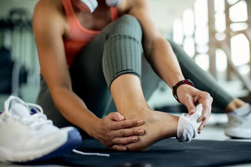 Sportive se tenant le pied après une blessure à l'entraînement